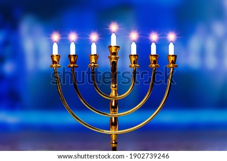 Menorah candelabra lit with burn candles on the last day of Hanukkah Jewish holiday.