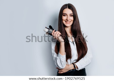 Makeup artist with brushes in hand on a white background Royalty-Free Stock Photo #1902769525
