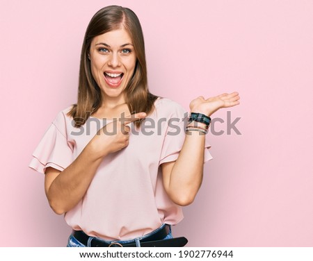 Beautiful caucasian woman wearing casual clothes amazed and smiling to the camera while presenting with hand and pointing with finger. 
