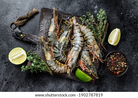 Raw black tiger prawns, shrimps and spices. Black background. Top view.