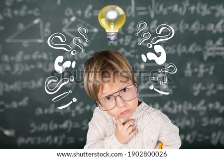 Smart kid with lightbulb. Brainstorming and idea concept. Little student boy on chalkboard background Royalty-Free Stock Photo #1902800026