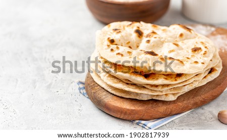 Homemade Roti Chapati Flatbread on gray concrete background. Freshly baked indian flatbread. Copy space for text. Royalty-Free Stock Photo #1902817939