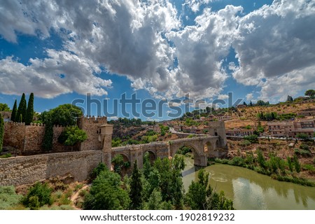 Panoramic cityscape of Toledo, Catilla La-Mancha, Spain, with dramatic cloudy sky. View of the river, bridge, hill and city main entrance  