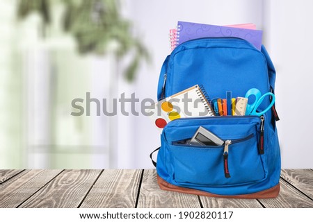 Classic school backpack with colorful school supplies and books on desk. Royalty-Free Stock Photo #1902820117
