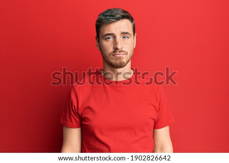 Handsome caucasian man wearing casual red tshirt depressed and worry for distress, crying angry and afraid. sad expression. 