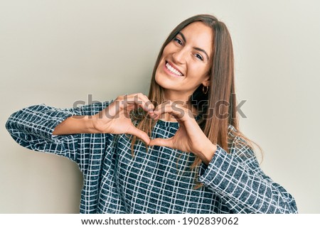 Young beautiful woman wearing casual clothes smiling in love doing heart symbol shape with hands. romantic concept. 