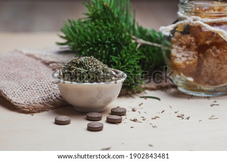 Tablets from natural ingredients, phyto pharmacy. A jar of honey, a bouquet of pine branches and herbal tea. Elements of traditional medicine. Royalty-Free Stock Photo #1902843481