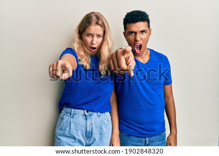 Young interracial couple wearing casual clothes pointing displeased and frustrated to the camera, angry and furious with you 