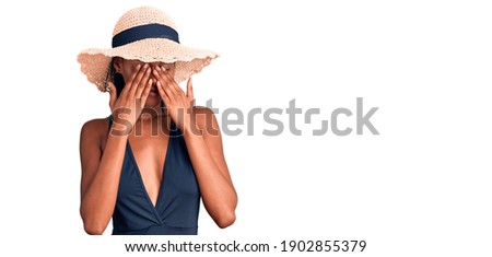 Young african american woman wearing swimsuit and summer hat rubbing eyes for fatigue and headache, sleepy and tired expression. vision problem 