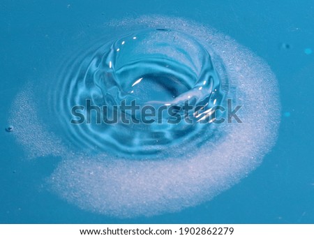the falling liquid creates patterns when hitting the surface of the water drop