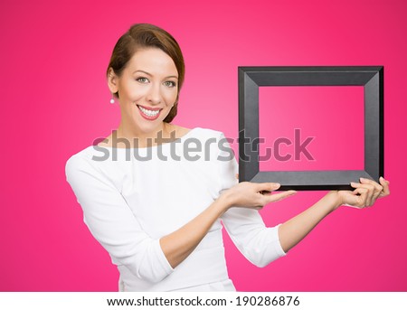 Closeup portrait, happy, confident, pretty, business woman, employee holding rectangular square empty blank picture frame, isolated pink background. Positive human emotion facial expression feelings