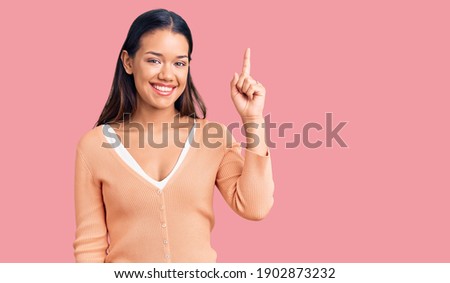 Young beautiful latin girl wearing casual clothes pointing finger up with successful idea. exited and happy. number one. 