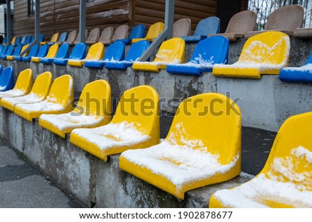 
Seats in the stadium in winter, colored chairs under the snow in the stadium