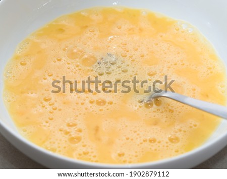 Yellow Beaten Eggs in White Plate with Fork