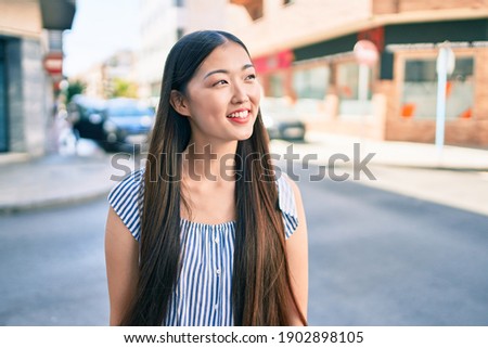 Young chinese woman smiling happy walking at street of city.