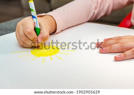 Education and school. Education and kindergarten concept. Cute little girl draws the sun with pencils
