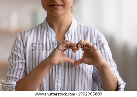 Cropped portrait of young female cardio patient expressing sincere gratitude appreciation to cardiologists volunteers charity givers. Close up of millennial woman posing to camera showing finger heart Royalty-Free Stock Photo #1902905809