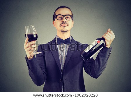 Portrait of a wine expert holding glass of red wine and a bottle 