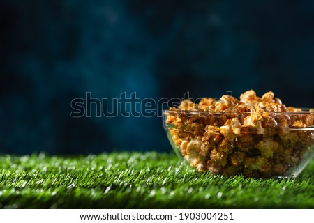Caramel popcorn in a transparent plate on a blue background Banner with space for an inscription. Relaxation and watching movies. Selling popcorn