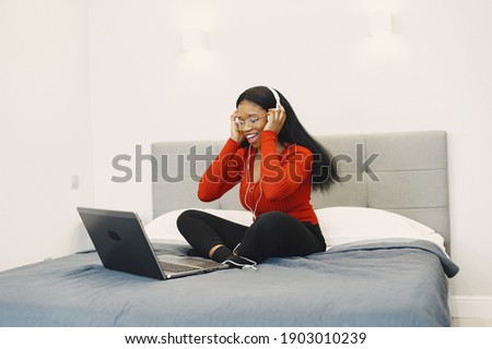 Woman with a laptop. International girl on a bed. Lady working online.