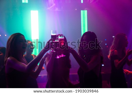 Silhouette image of people dance in disco night club to music from DJ on stage . New year night party and nightlife concept .
