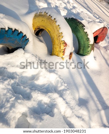Old rubber car tires in the snow in winter.