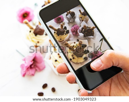 Girl makes a photo of cupcakes on a smartphone