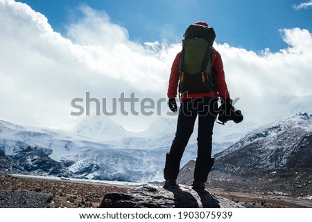 Woman hiker with camera in winter high altitude mountains