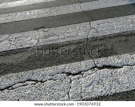 Detail of a pedestrian crossing with pedestrian crossing and damaged asphalt