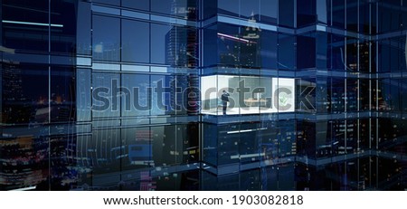 Businessman using mobile phone to talk business in office. View from the outside 3D rendering commercial skyscraper. Royalty-Free Stock Photo #1903082818