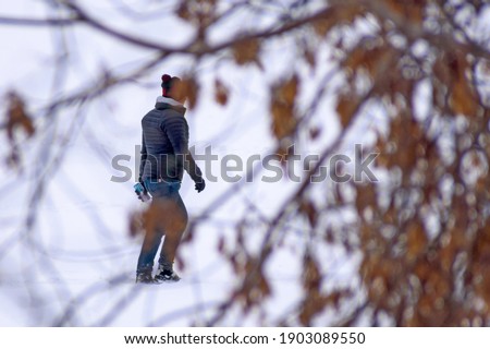 A young man with medical supplies walks on the snow-covered ice of the river