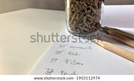 The pellets feed in a glass bottle are placed on a white table.