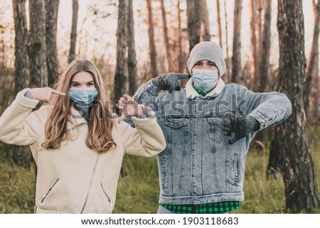 A guy and a girl in medical masks in a pine forest