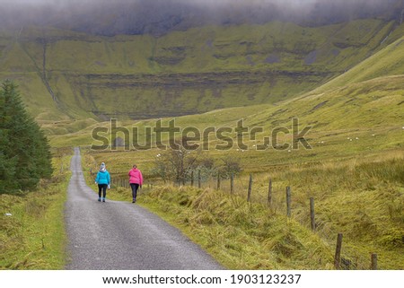Two women walking on a road with beautiful scenery around them. Gleniff Horseshoe drive loop county Sligo, Ireland