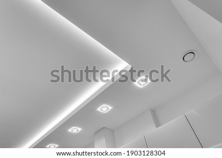 suspended ceiling with halogen spots lamps and drywall construction in empty room in apartment or house. Stretch ceiling white and complex shape. Royalty-Free Stock Photo #1903128304