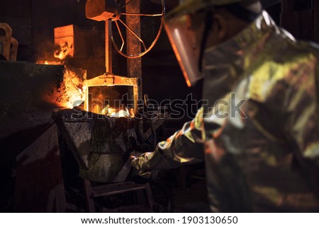 Worker In protective clothing checking molten iron In foundry. Royalty-Free Stock Photo #1903130650