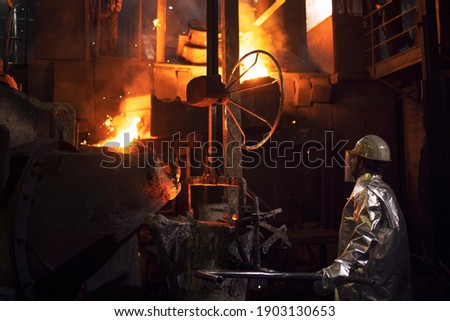 Hard work in foundry and melting iron in furnace. Workers controlling iron smelting in furnace. Royalty-Free Stock Photo #1903130653