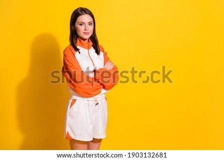 Photo portrait of serious woman with folded arms looking at blank space isolated on vivid yellow colored background