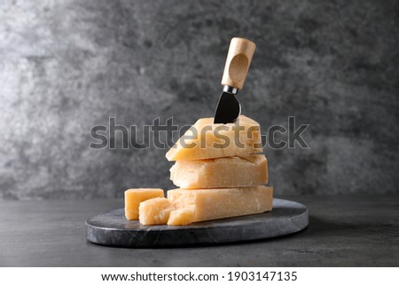 Parmesan cheese with board and knife on grey table Royalty-Free Stock Photo #1903147135