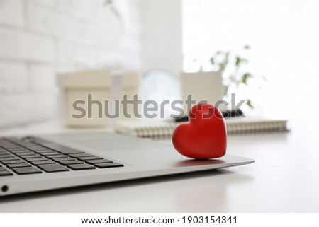 Red heart on laptop in office, space for text. Valentine's day celebration
