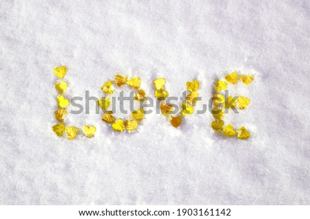 valentine's day concept: word love laid out with hearts on snow.