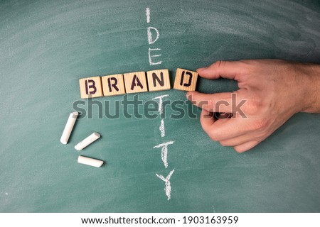 Brand and Identity concept. Text from letters of the wooden alphabet on a green chalk board Royalty-Free Stock Photo #1903163959