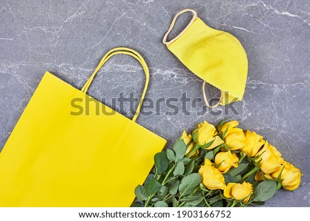 Yellow roses, yellow paper bag, yellow protective mask on gray background. Valentines day,Mothers day,Womens day flat lay. Spring, new normal. Seasonal allergy