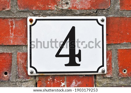 A white house number plaque, showing the number four (4)