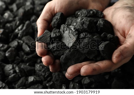 Man holding coal in hands over pile, closeup Royalty-Free Stock Photo #1903179919