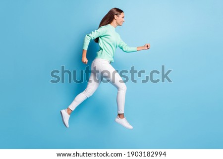 Full length profile photo of purposeful lady girl wear casual outfit jumping high hands fists isolated blue color background