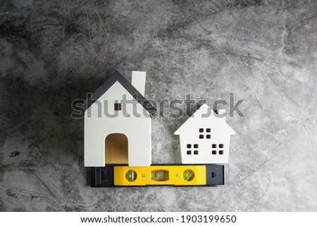 Wooden white house toy and construction tools on Gray-black cement floor background with copy space.Real estate concept, New house.Home repair concept