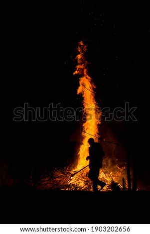 a man by a big fire at night
