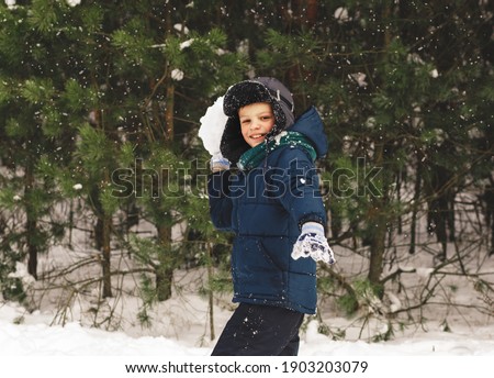 Cute boy plays with snow in a beautiful snow park in winter