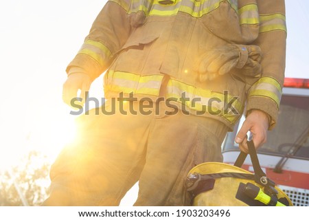 Fire fighter holding helmet against strong lens flare